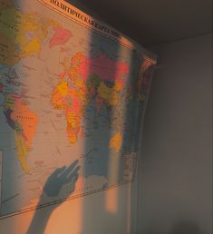 a person's shadow is cast on the wall next to a large world map