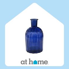 a blue glass vase sitting on top of a white and blue sign that says at home