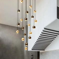 a modern chandelier hanging from the ceiling in a room with white walls and stairs