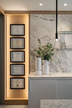 a marble counter top with vases and framed books on the wall behind it in a modern kitchen