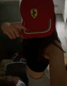 a woman wearing a red hat with a ferrari emblem on it's brim