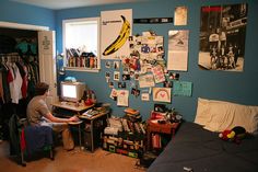 a person sitting at a desk with a computer in front of a monitor and some pictures on the wall