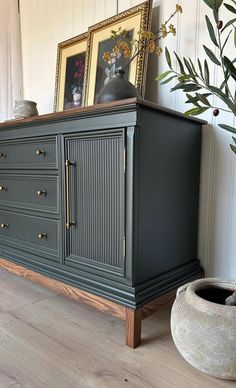 an old dresser is painted green and has gold hardware on the top, along with a potted plant