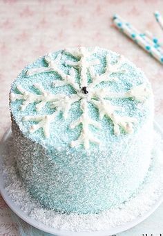 a frosted cake sitting on top of a white plate next to a blue and white snowflake decoration