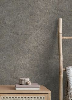 a wooden table sitting in front of a gray wall with a bamboo chair next to it