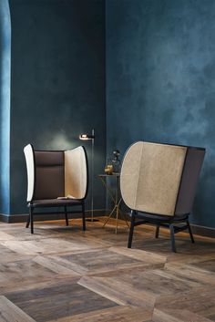 two chairs sitting next to each other on top of a hard wood floor in front of a blue wall