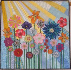 a quilted wall hanging with colorful flowers and butterflies in the sunbeams on it