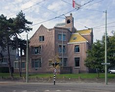 an old brick building with a clock tower on the top and two storyed houses in the background