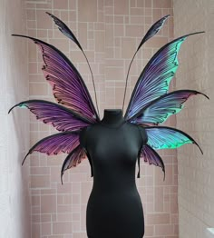 a black mannequin with purple and green butterfly wings on it's head