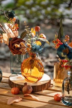 three vases filled with flowers sitting on top of a wooden table next to each other