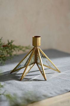 a small glass candle holder sitting on top of a white cloth covered tablecloth next to a pine branch