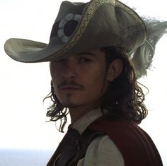 a young man wearing a pirate costume and a hat with feathers on it's head