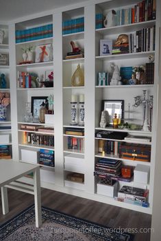 a living room filled with lots of white bookshelves