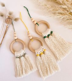 three wooden rings with tassels are sitting next to some dried flowers and grass