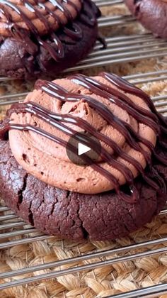 two chocolate cookies with drizzled chocolate icing sitting on a cooling rack