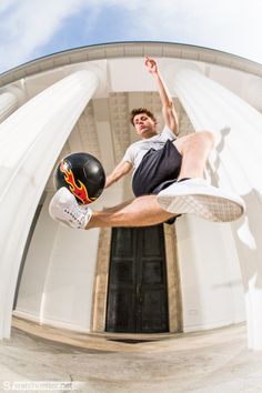 a man is jumping in the air with a skateboard and ball on his feet