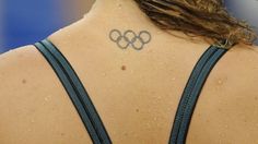 the back of a woman's neck with an olympic symbol on it