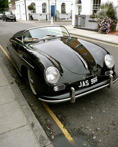 an old black sports car parked on the side of the road