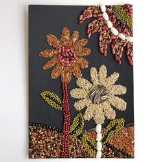 beaded flowers and beads are displayed on a dark blue background with brown trimmings