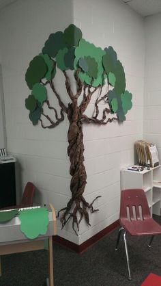 a classroom with chairs, desks and a tree cut out on the wall above it