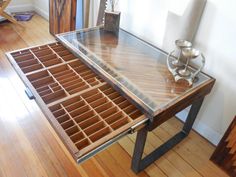 a wooden table with drawers underneath it on a hard wood flooring area next to a white wall