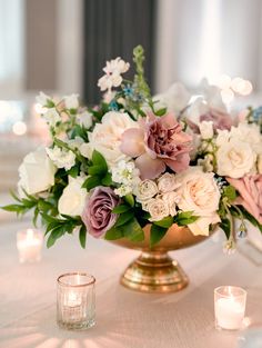 a vase filled with lots of flowers on top of a table next to some candles