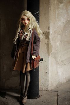 a doll is standing next to a pole with a purse on it's shoulder