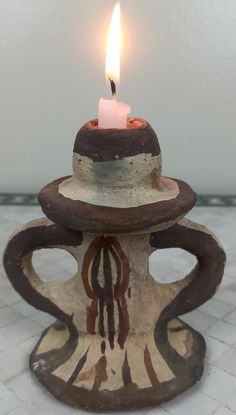 a lit candle sitting on top of a ceramic cup