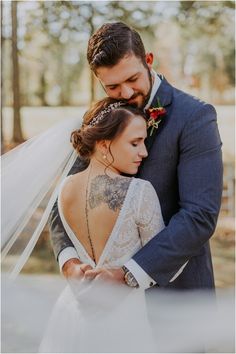 a bride and groom embracing each other in the woods