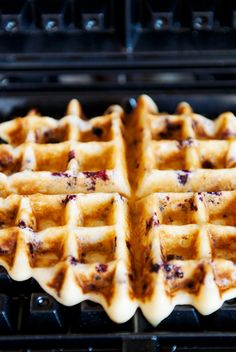 a waffle sitting on top of an open grill with syrup and cranberry toppings