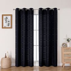 a black curtain hanging on the side of a window next to a wooden table and chair