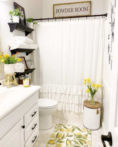 a white bathroom with black and yellow decor on the shower curtain, rugs and towels