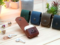 an assortment of earbuds and leather cases sitting on a table next to plants