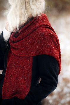 a woman with white hair wearing a red shawl and black jacket in the snow