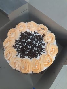 a cake with white frosting and black sprinkles in a cardboard box