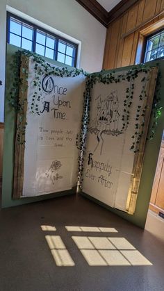 an open book sitting on top of a floor next to a window with ivy growing over it