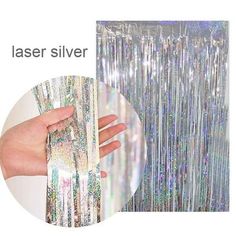 a hand that is holding some tinsel silver foil curtain with it's hands