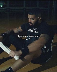 a man sitting on the ground holding a tennis racquet in one hand and an inscription that reads, i guess you know now