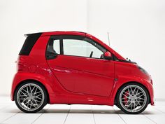 a red smart car parked in a white room