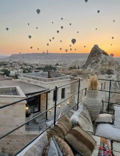 hot air balloons are flying in the sky above a city at sunset or dawn,