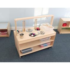 a child's play table with bowls, cups and spoons on it in a room