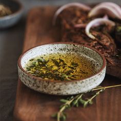 an image of a bowl of soup on a cutting board with garlic and herbs in it