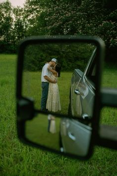 a man and woman standing next to each other in front of a rear view mirror