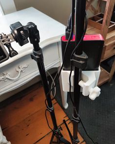 there are two tripods on the ground next to a desk with a phone and camera