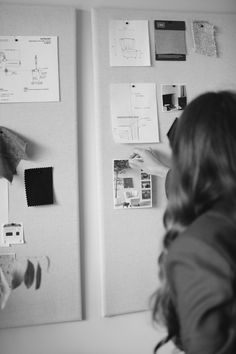 a woman standing in front of a refrigerator with magnets and papers on the wall