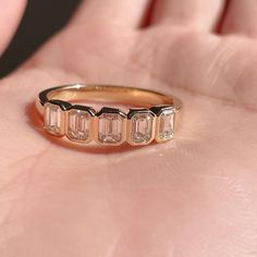 a woman's hand holding a gold ring with three baguettes