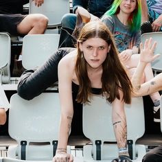 a woman sitting in the bleachers with her legs spread out and hands up