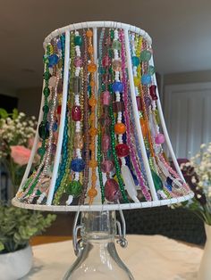 a lamp that is on top of a table with beads hanging from the lampshade