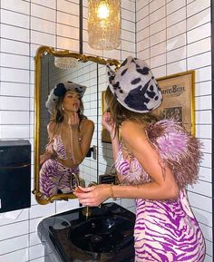 a woman in a zebra print dress is looking at her reflection in the bathroom mirror