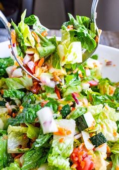 a salad with lettuce, carrots and other vegetables being held by a fork